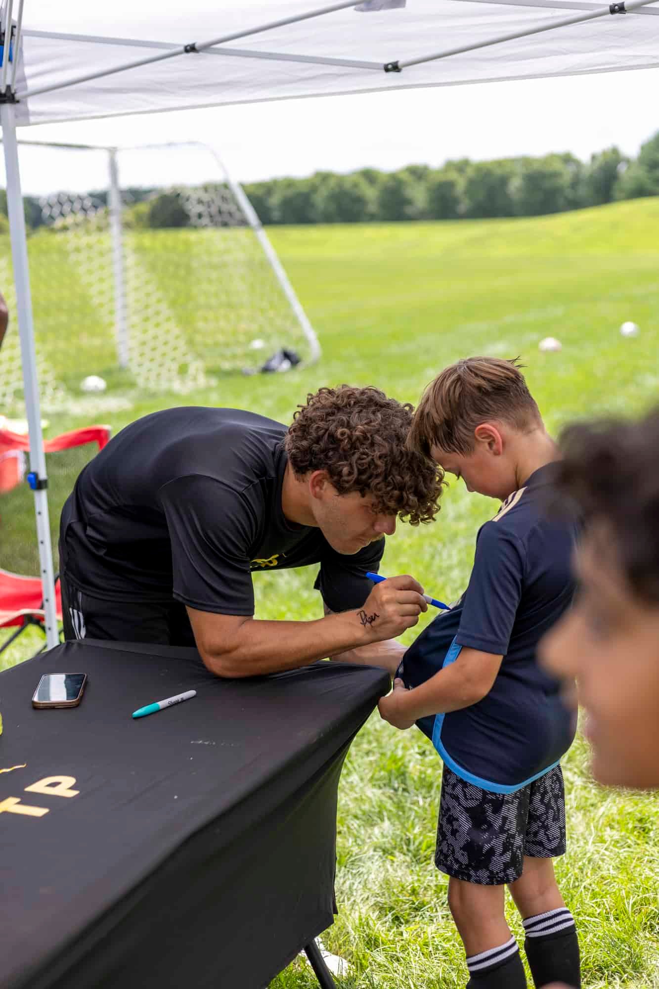 Coach signing gear at PTP soccer camps