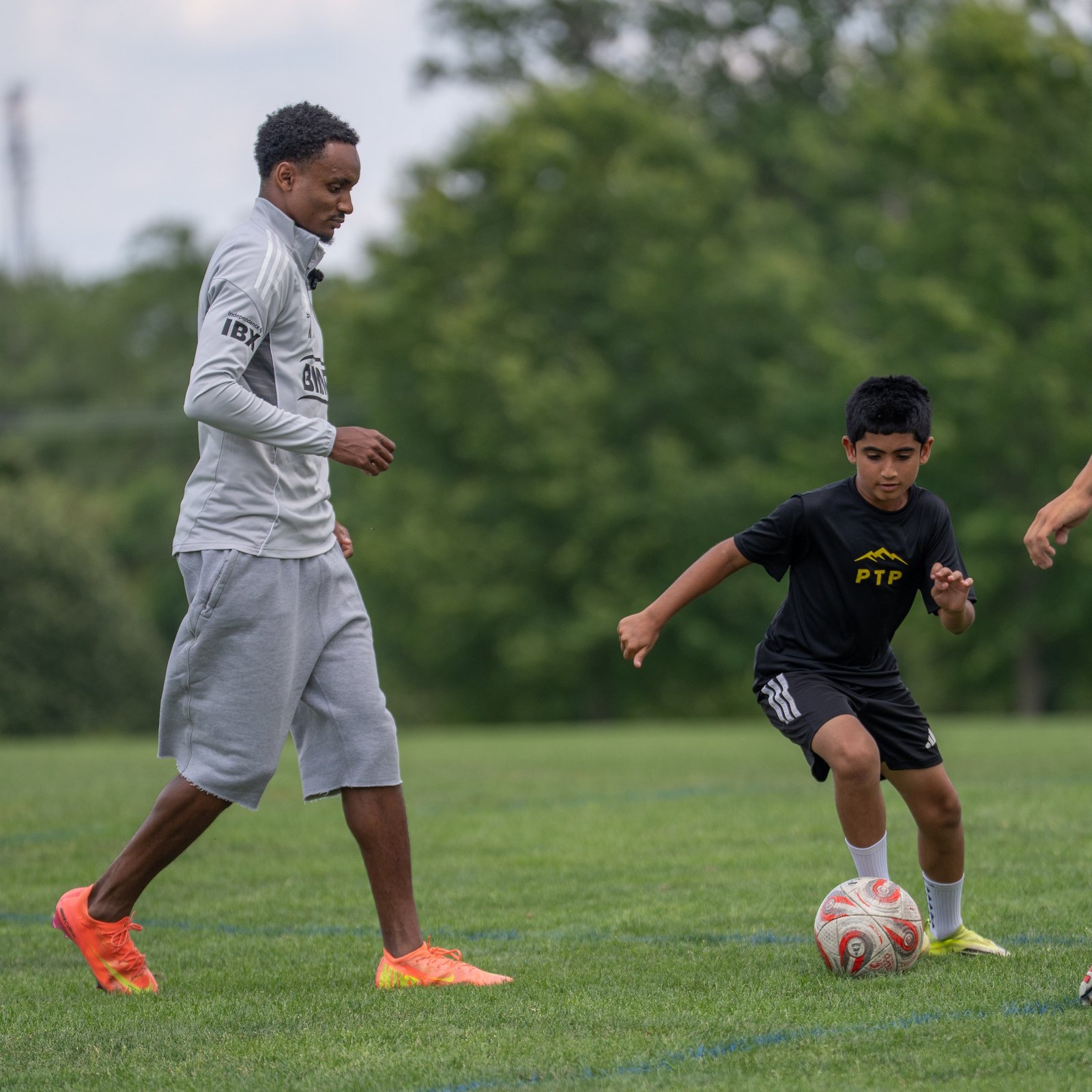 Camper in a black shirt dribbles beside a visiting player