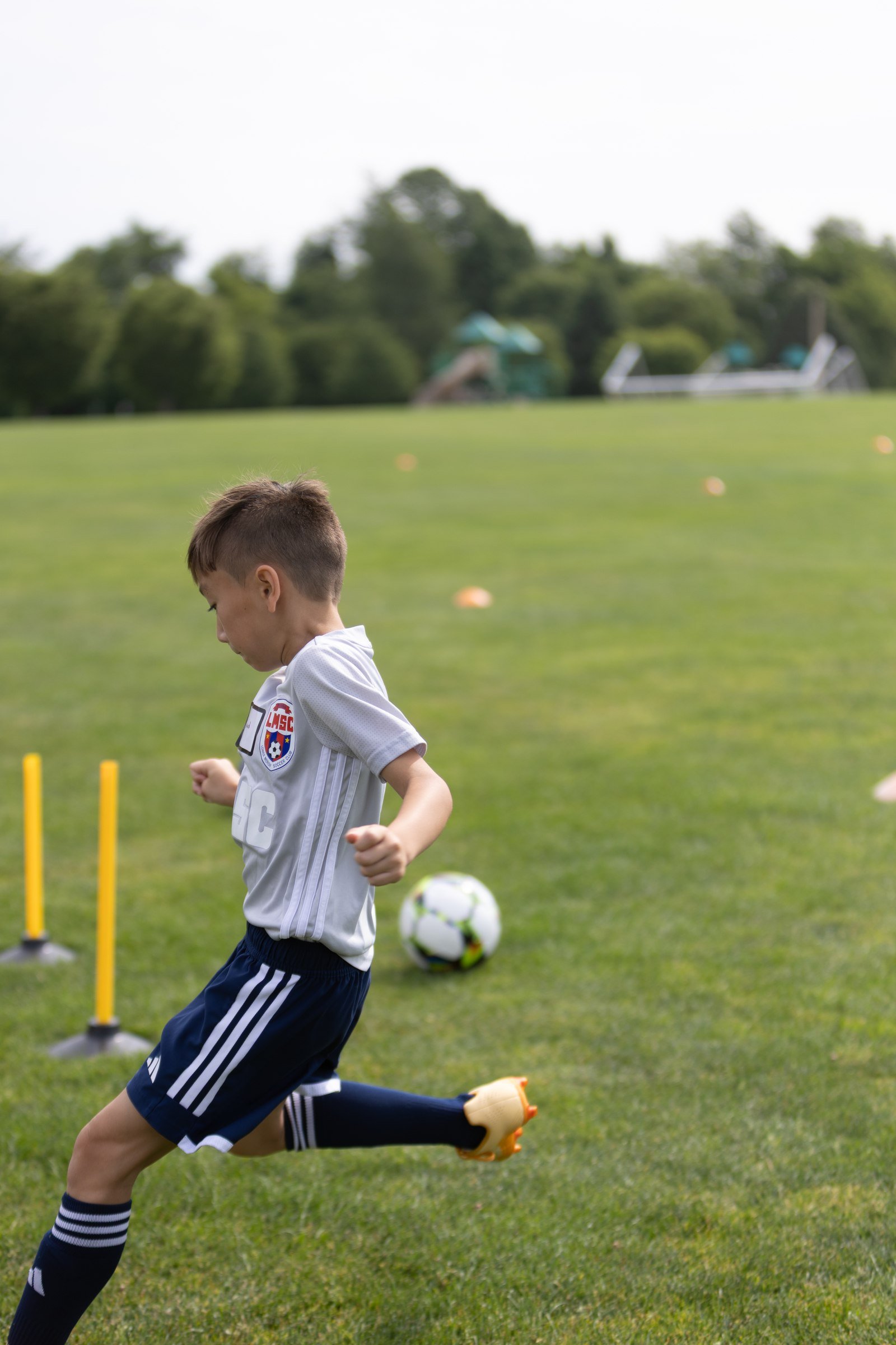 Camper in a gray shirt dribbles between cones and training poles