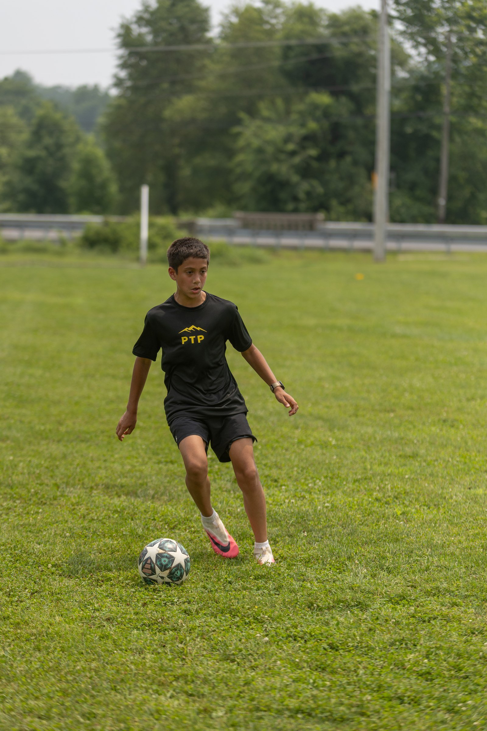 Camper in black dribbles with the ball while a coach watches