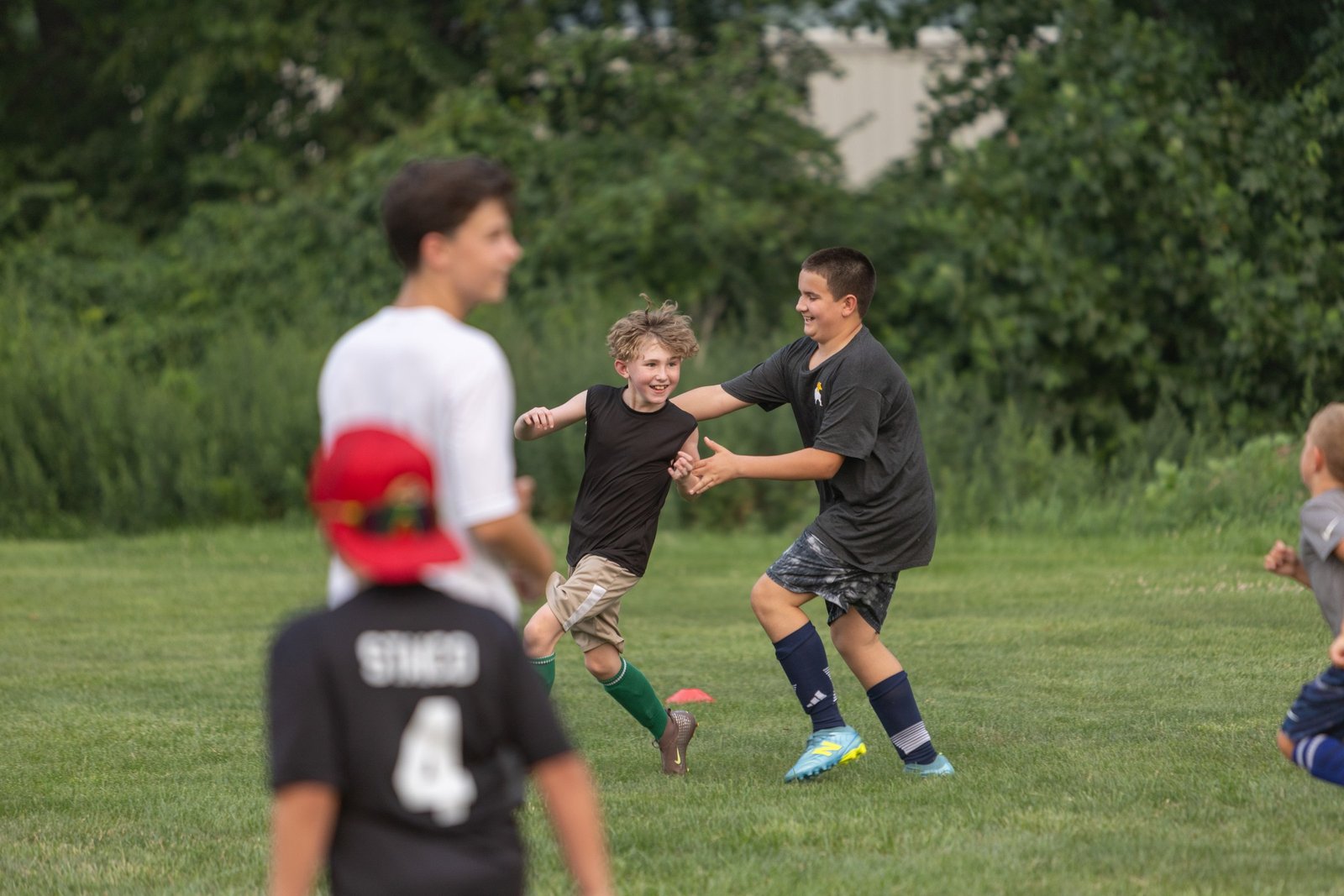 Campers and a coach contest a ball during a small sided