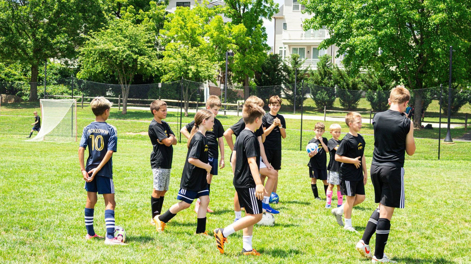 Campers and a coach gather together beside soccer goals