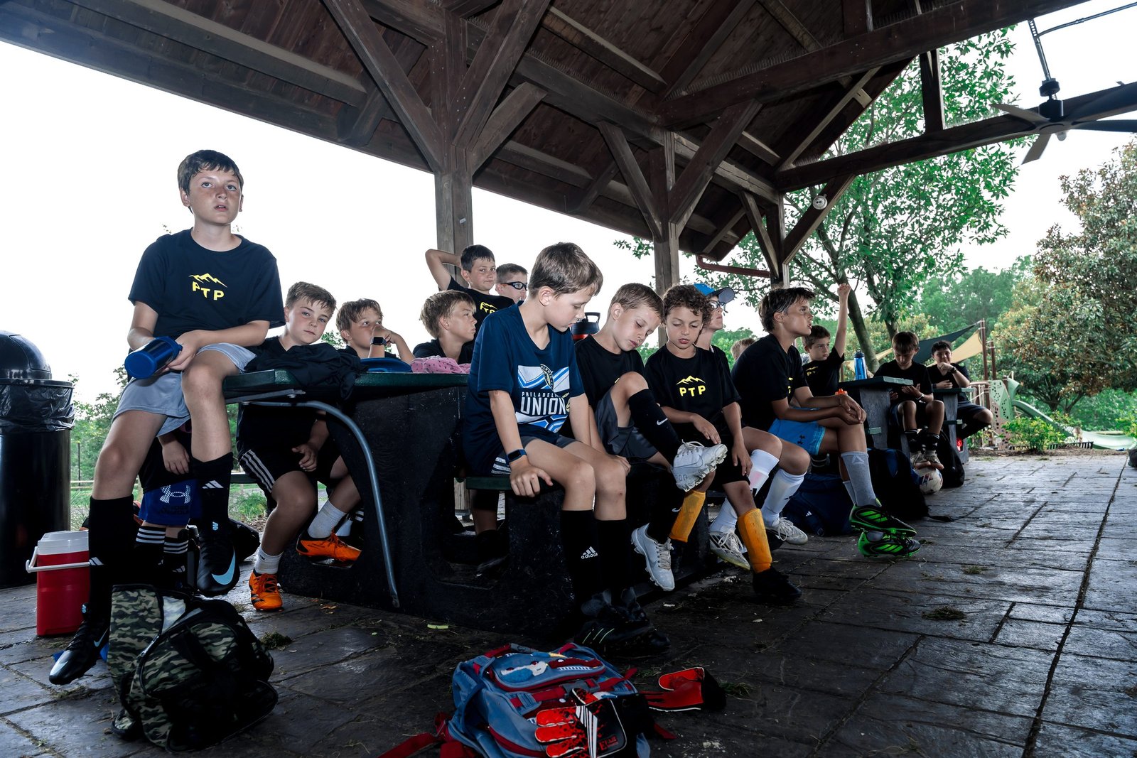 Campers and coaches in black PTP shirts gather on benches